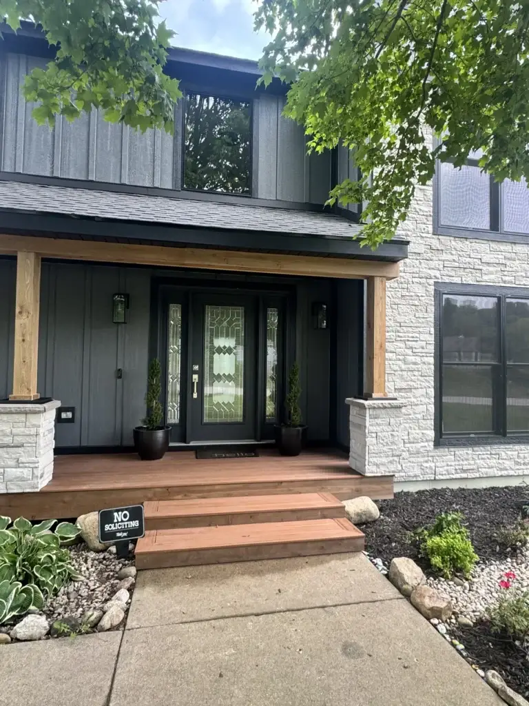 After: covered front entry with cedar beam, stone piers and glass-panel door