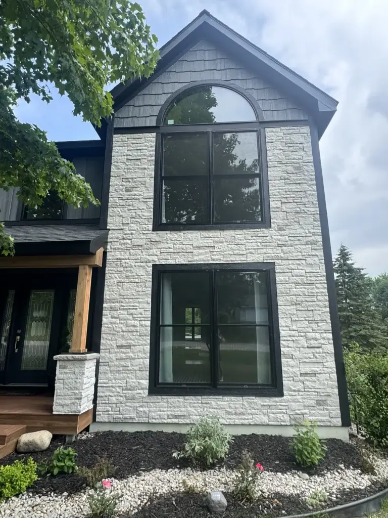 After: stone gable with black arched windows and shake siding above