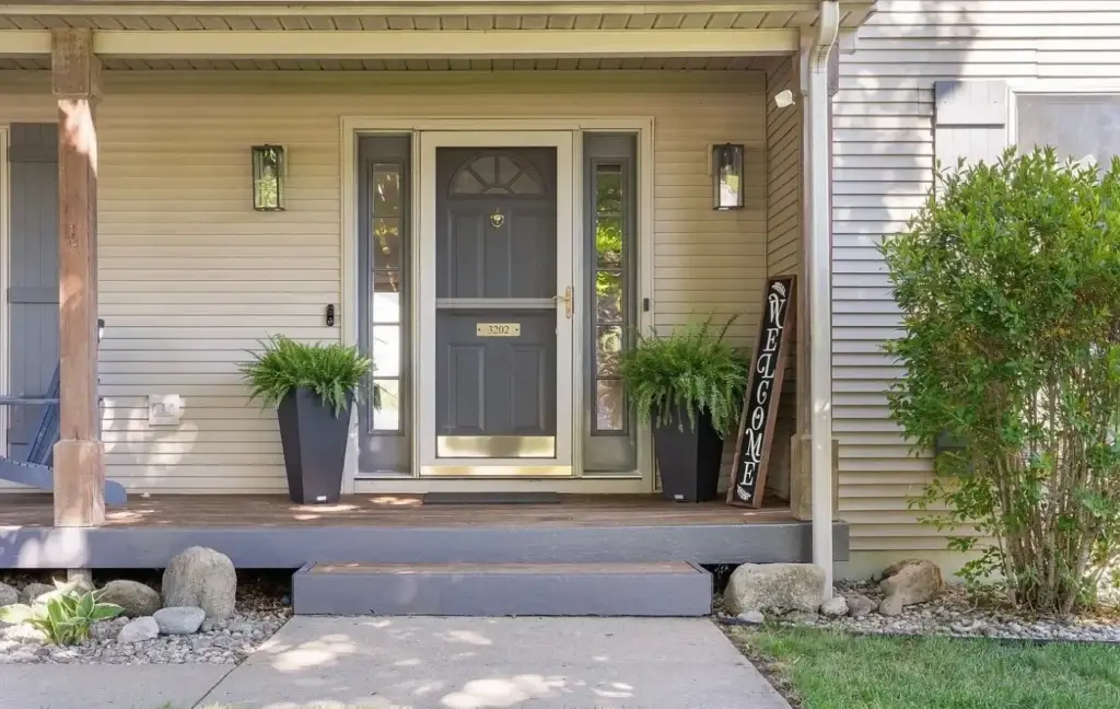Before: front porch with gray door and beige siding